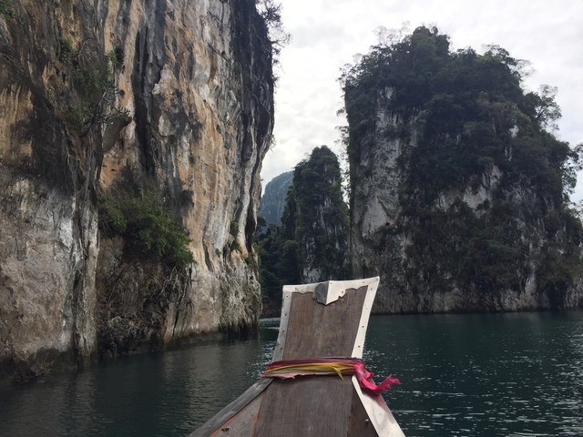 Longtail boat navigating through rocky passage.
