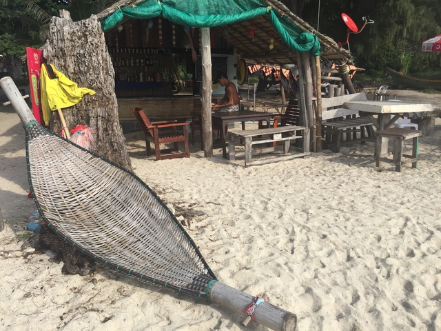 Small beachside bar with wooden tables and chairs.