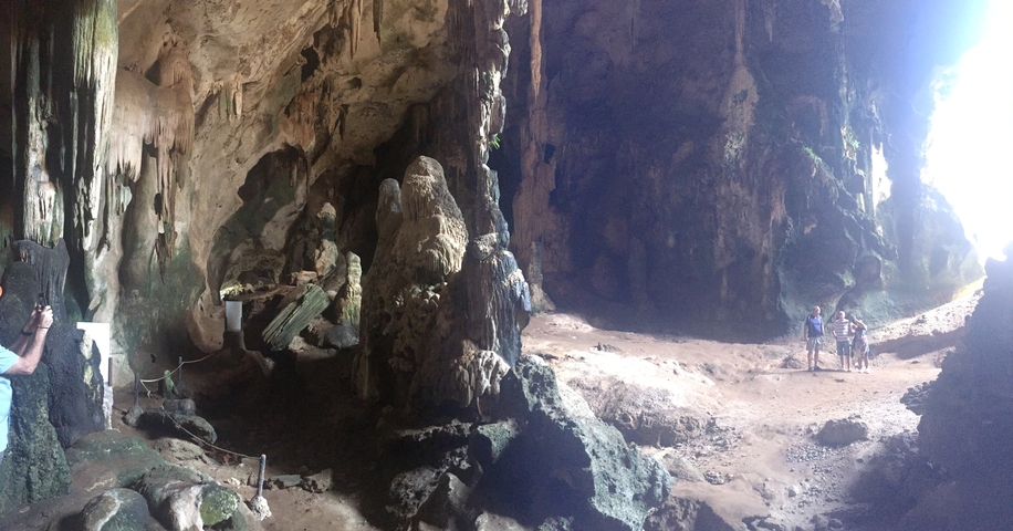 Cave with rock formations and tourists exploring.