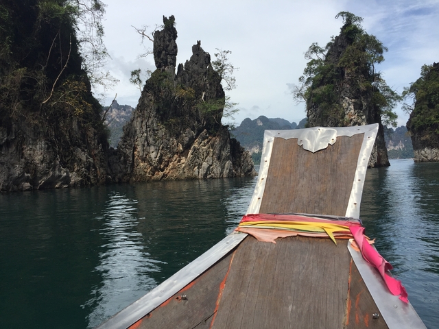 Longtail boat cruising through narrow cliffs.