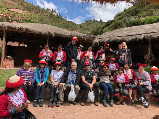 Group photo of people wearing traditional clothing in a rural setting.