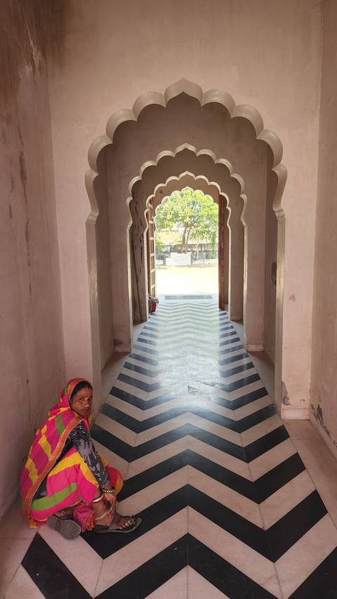 Woman in colorful clothing sitting in an archway.