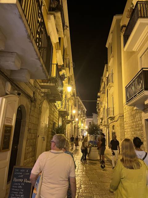 People walking down a narrow street at night.