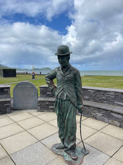 A statue wearing a hat and long coat holding a cane.