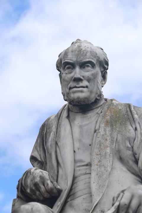 A marble statue of a person wearing period clothing.