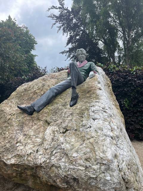 A statue of a person sitting on a large rock.