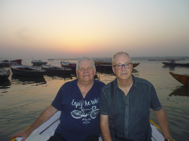 Two men on a boat with a sunset in the background.
