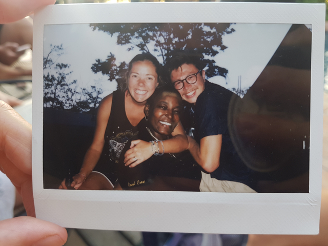 Polaroid photo with three people embracing and smiling.