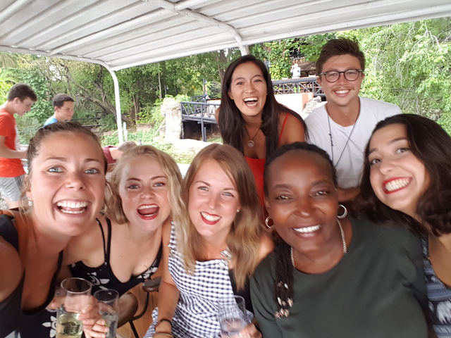 Group of people smiling and posing closely together under a canopy.