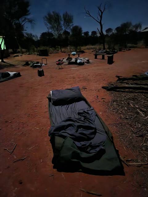 Campsite setup with bedding and chairs on the ground.