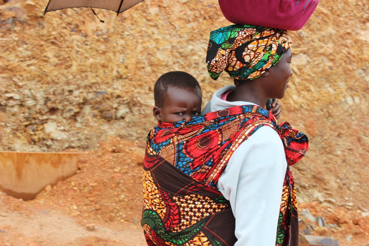 A person carrying a child on their back, both wearing colorful clothing.