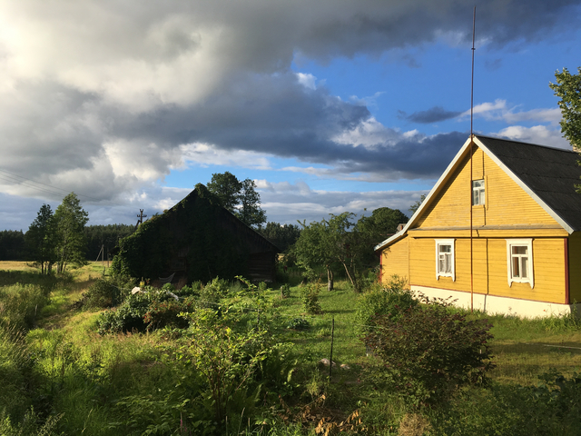 Country house with a garden under a partly cloudy sky.