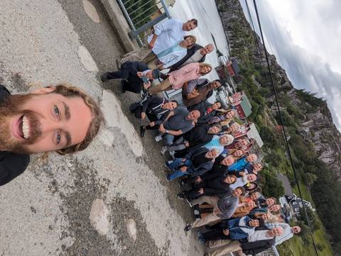 Group of travelers posing near a scenic lakeside view.