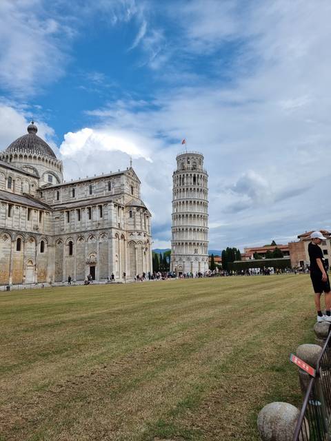 Leaning tower and cathedral under a partially cloudy sky.