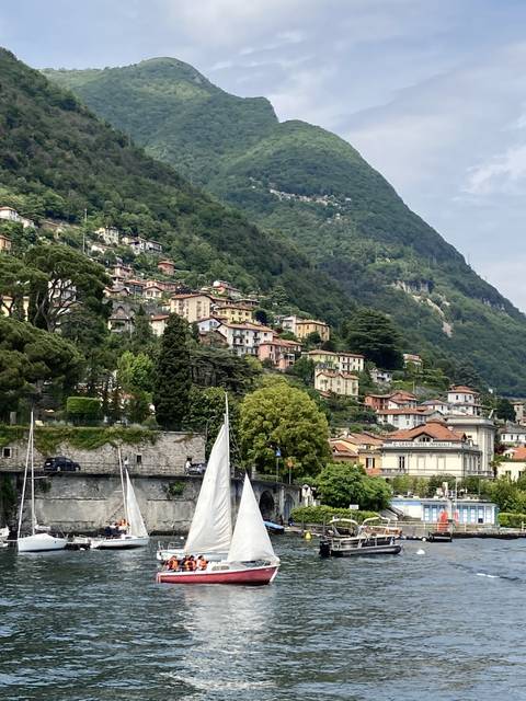 Sailboat on a lake with a backdrop of hills and buildings.