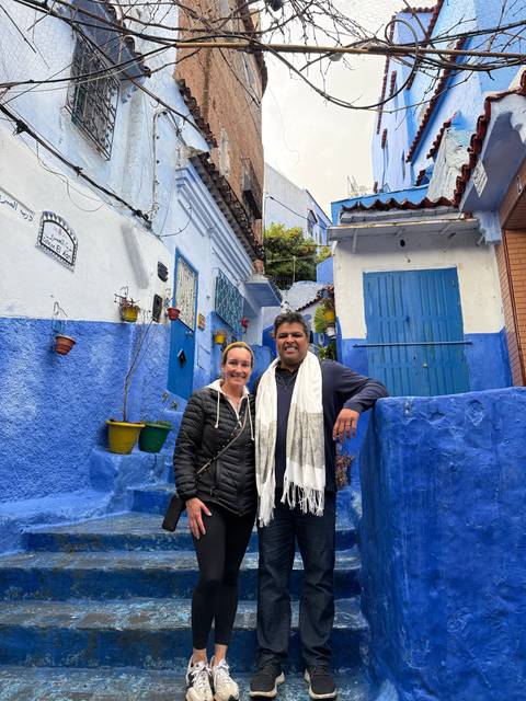 People posing in a vibrant blue alley with decorative objects.