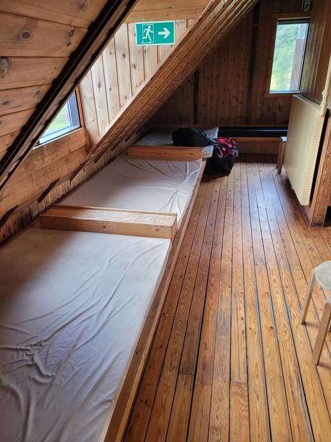 Interior of a wooden cabin with a bunk bed and luggage.