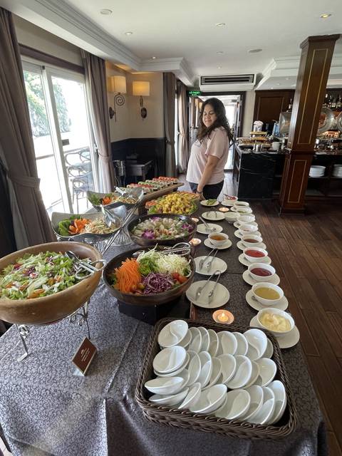 Buffet table with various foods and a person serving.