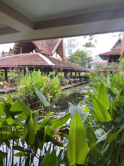 Pathway through a lush garden with traditional buildings.