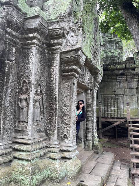 Person amid ornate stone temple ruins.
