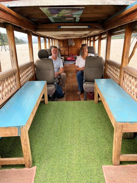 Two people sitting on a boat with a river view.