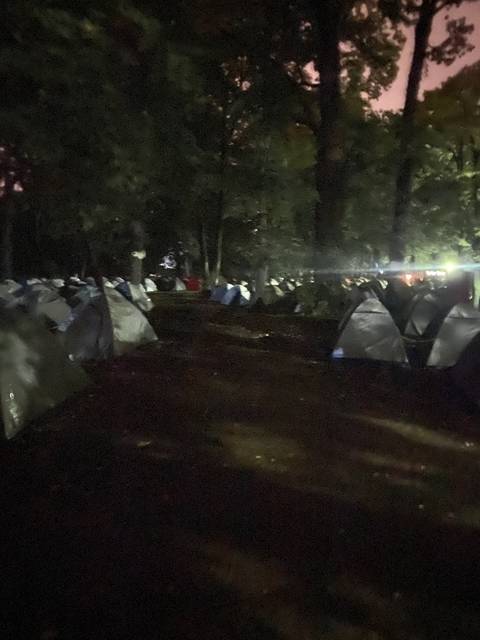 Nighttime view of a campsite with tents among trees.
