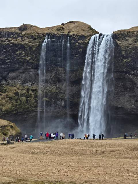 Waterfall cascading down a cliff with people nearby.