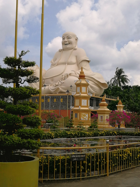 Statue of a large Buddha with surrounding greenery.