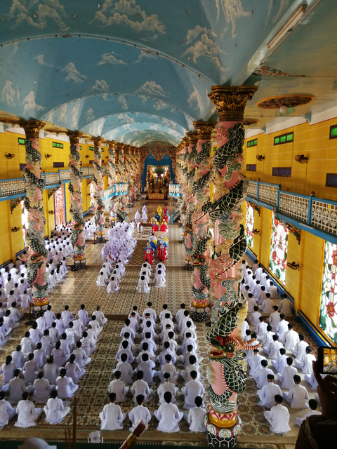 Ornate temple interior filled with people participating in a ceremony.