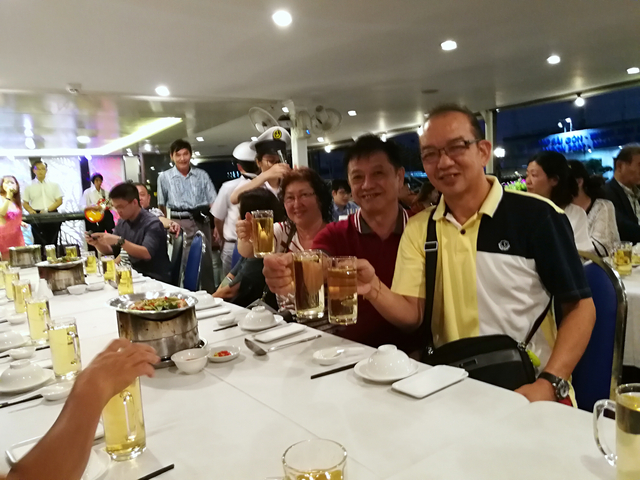 People raising glasses in a toast at a dining setting.