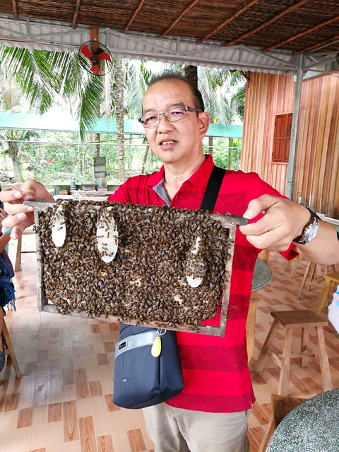 Man showing a honeycomb with bees.