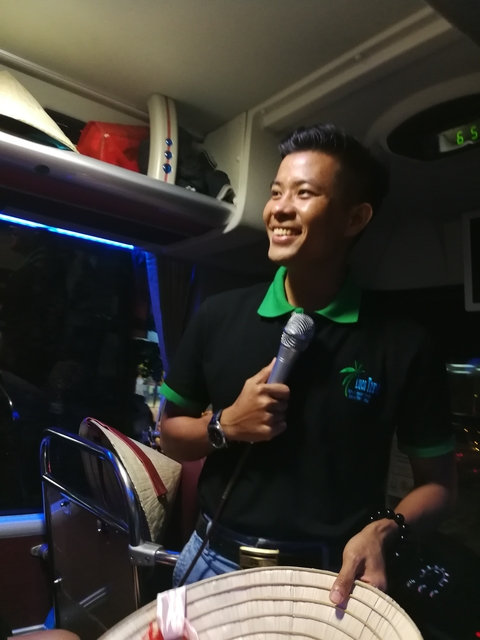Man speaking into a microphone inside a vehicle.