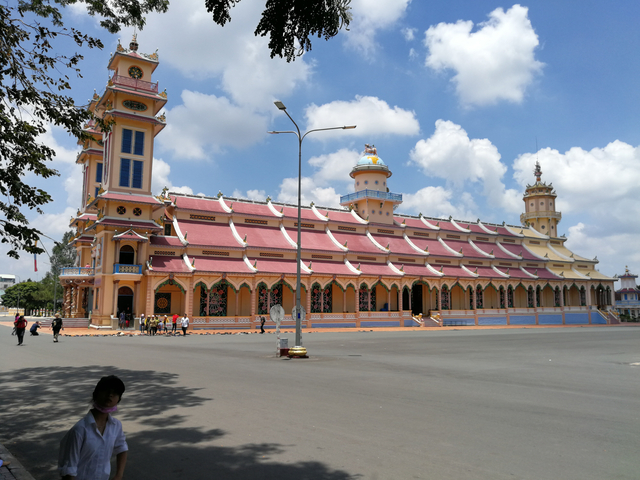 Large colorful temple with intricate roof, on a sunny day.