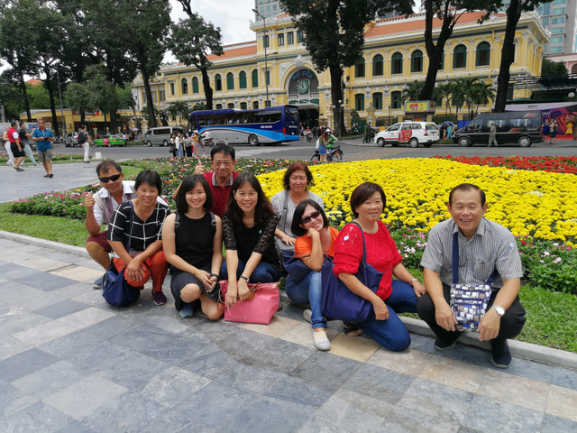 Group of people posing in front of a flower garden.
