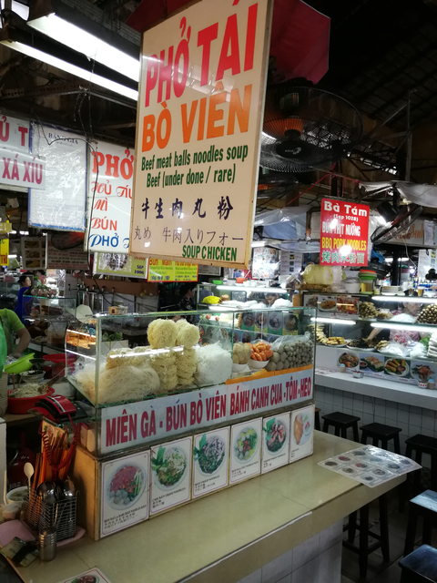 Busy food market with various displays and signs.