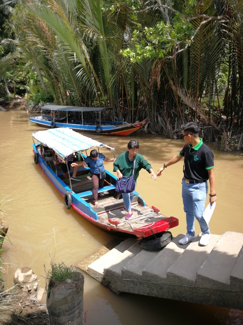 People getting off a small river boat with assistance.
