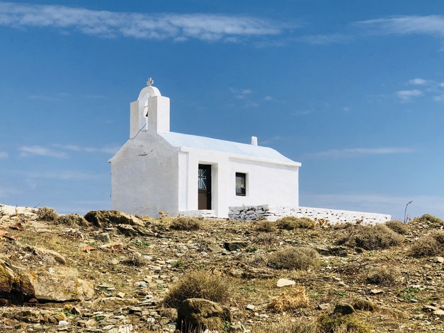 Small white chapel on a rocky terrain under a clear blue sky.