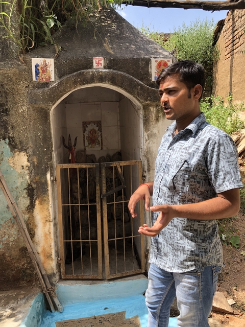 Person standing next to a small shrine or temple.