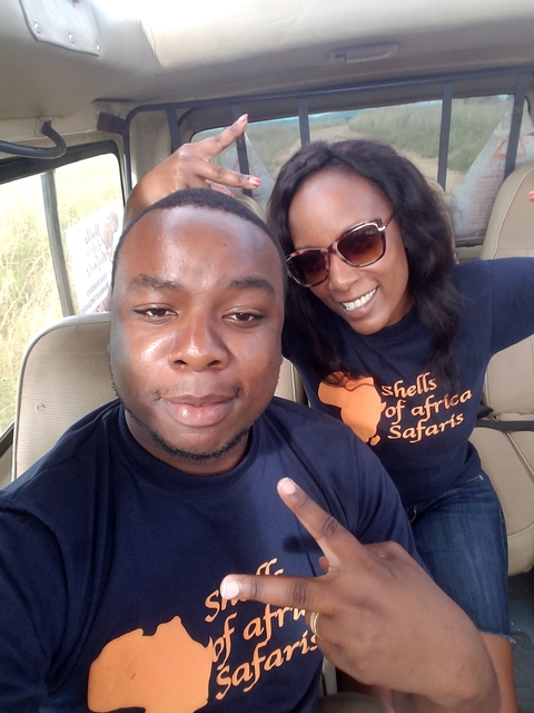 Two people smiling inside a vehicle, wearing branded t-shirts.