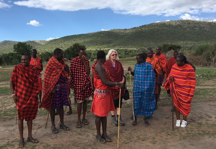 A group of locals and a tourist dressed in traditional clothing in an open field.