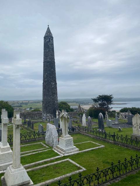 Cemetery with old headstones and a distant view of the sea.