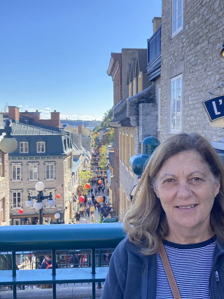 Une personne debout sur un balcon avec vue sur les rues de la ville de Québec en contrebas.