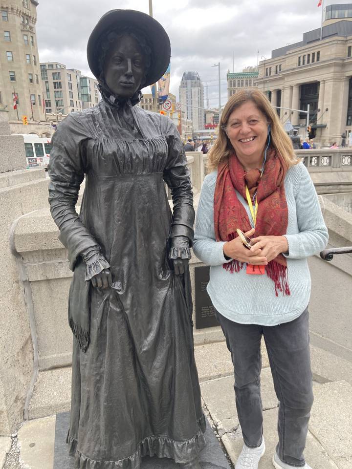 Une personne posant à côté d'une statue historique.