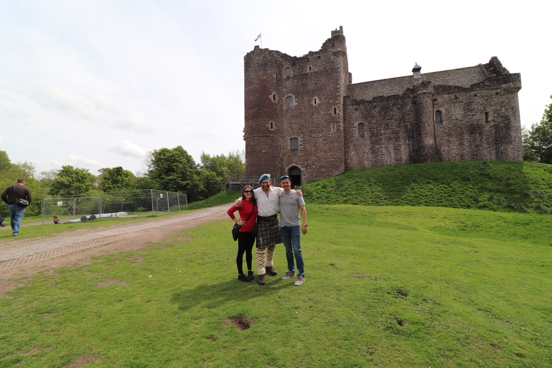Trois personnes avec un grand château historique en pierre.