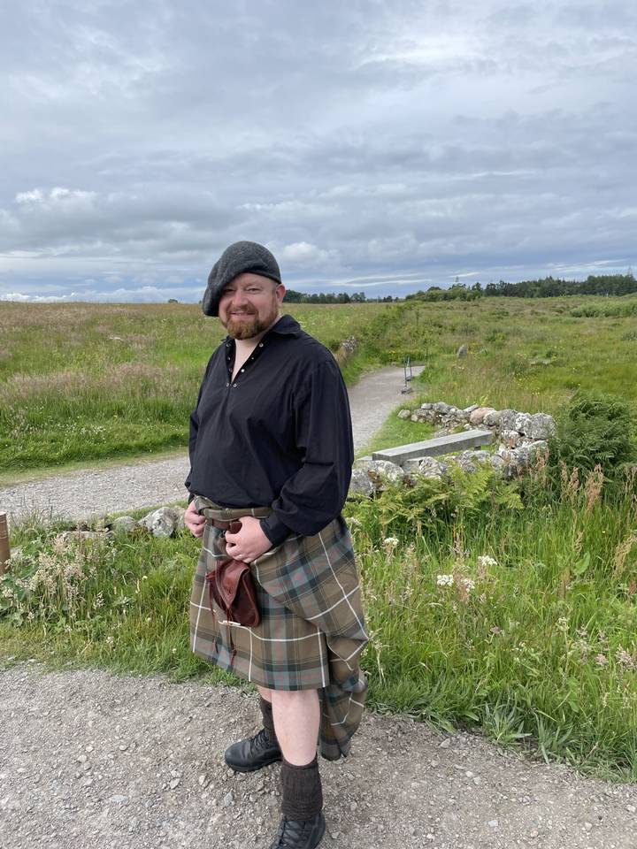 Homme portant une tenue écossaise traditionnelle debout à l'extérieur.