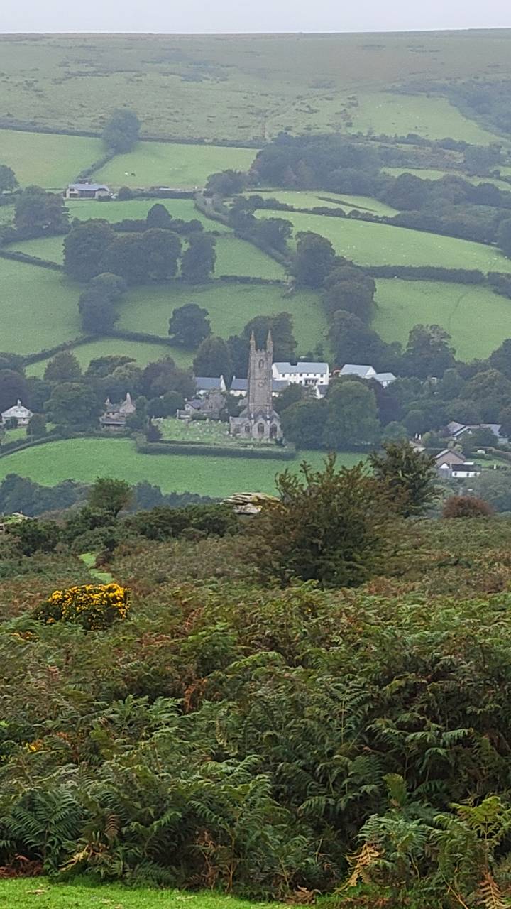 Vue lointaine d'un clocher d'église au milieu de collines verdoyantes ondulantes