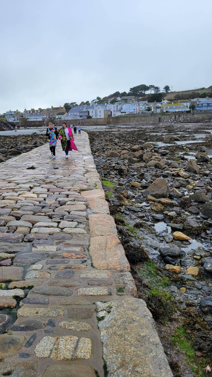 Un sentier de pierre longeant une côte rocheuse avec des gens qui marchent