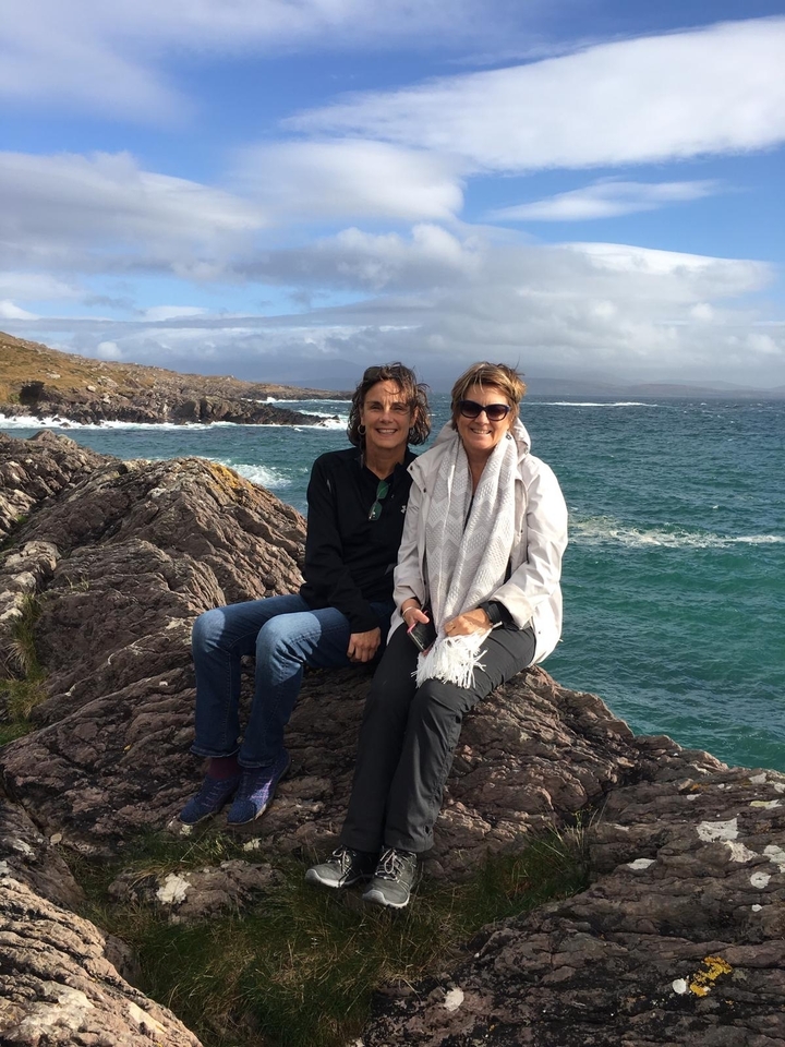 Deux femmes assises sur des rochers au bord de la mer.