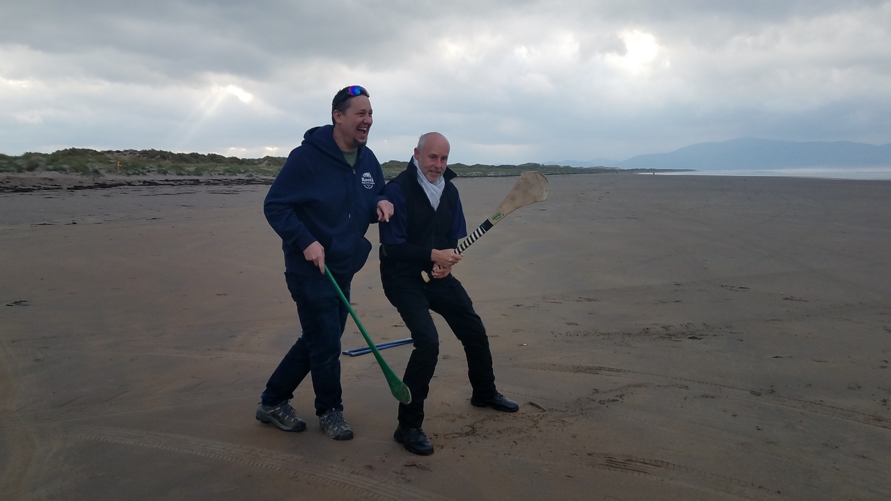 Deux hommes jouent avec des crosses de hurling sur une plage.