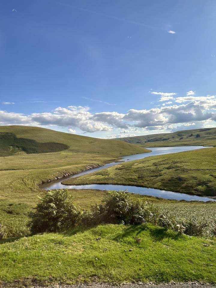 Des collines verdoyantes avec une rivière qui les traverse.